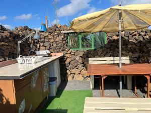 an outdoor kitchen with an umbrella and a bench at The Secret Garden Lanzarote in Haría