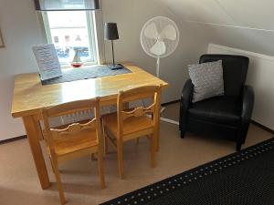 a wooden desk with a chair and a table and a fan at Håverud Hostel in Håverud