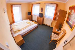 a small bedroom with a bed and two windows at Penzion Černej pták in Jindřichŭv Hradec