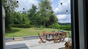 a patio with a table and chairs and a yard at Maison d'hôte in Grez-Doiceau