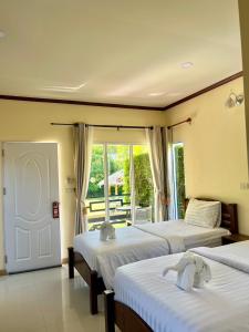 a bedroom with two beds and a door with a balcony at Koh Yao Modern Inn -SHA Plus in Ko Yao Yai
