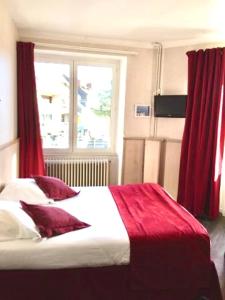 a bedroom with a large bed with red curtains at Logis Hôtel Restaurant Le Palous in Baraqueville +35 photos