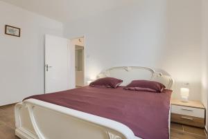 a white bed with purple sheets and two pillows at David in Mali Lošinj +22 photos