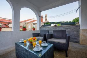 a patio with two chairs and a table with fruit on it at David in Mali Lošinj