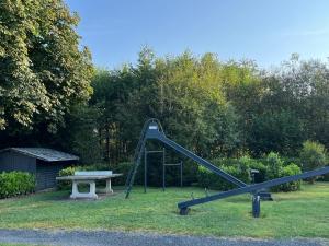 a playground with a slide and a bench and trees at Ferienwohnungen Hoefchen in Eckfeld
