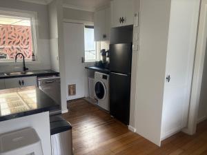 a kitchen with a black refrigerator and a dishwasher at Willow Place in Mornington