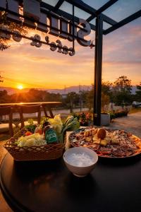 a table with two plates of food on it with the sunset at The Sunnery Ville in Lom Kao