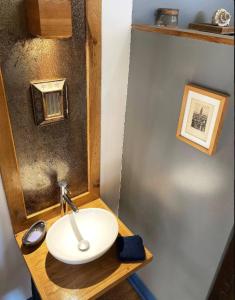a bathroom with a white sink on a wooden counter at La Ferme Bugiste - Maison de caractère in Belley
