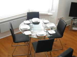 a dining room table with black chairs and white dishes at High Street Suites 3 in Ventnor +2 photos