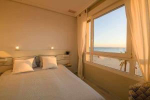 a bedroom with a window with a view of the beach at Preciado apartamento con vistas frontales al mar in Cádiz