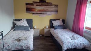 two beds in a room with pink curtains at Rudiferienwohnung in Büdingen