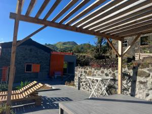 a wooden pergola with a table and bench on a patio at Casa Picobello in Calheta de Nesquim
