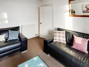 a living room with two black leather couches at Culquhasen in Gillespie