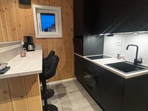 a kitchen with a sink and a counter top at Unik og moderne microhytte med utsikt mot havet 40 A Otterlei Resort in Longva +39 photos