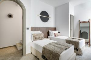 two beds in a white room with a mirror at Koniko Santorini Private Pool Villas in Vóthon +93 photos