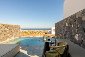 a patio with a table and chairs and a pool at Koniko Santorini Private Pool Villas in Vóthon
