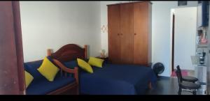 a living room with a blue couch with yellow pillows at Suíte da Lagoa in Araruama