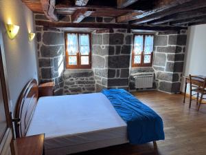 a bedroom with a bed in a stone wall at Le relais de Lustrande in Brezons