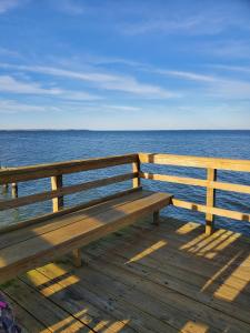 a wooden bench sitting on top of a wooden pier overlooking the ocean at The Bay House in Shady Side