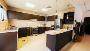a large kitchen with wooden cabinets and a large island at Family Friendly Villa in Abu Dhabi