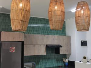 two pendant lights hanging over a kitchen with green tiles at Anyomi Zen in Gqeberha