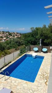a blue swimming pool with two tables at Villa Marina in Kalamitsi