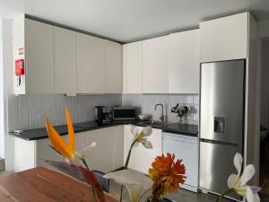 a kitchen with white cabinets and a stainless steel refrigerator at Casa Picobello in Calheta de Nesquim
