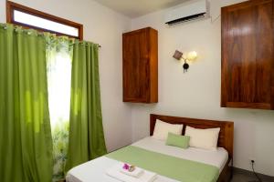 a bedroom with a bed with green curtains and a window at Maison d'hôte Chez Vané in Sambava