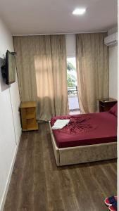 a bedroom with a bed with red sheets and a window at Hotel Te Bakja in Tushemisht +8 photos