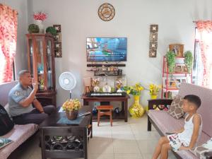 a man and a child sitting in a living room at Naybe's Room rentals in Dapa