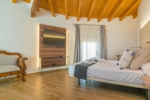 a bedroom with a bed with a television and a chair at TI Central Maria in Maria de la Salut