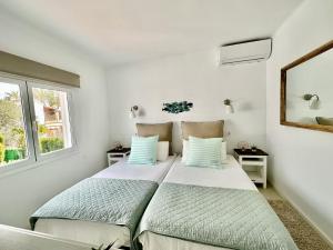 two beds in a white room with two windows at Villa Colibrí, con piscina privada para 6 personas in Santa Ponsa +34 photos
