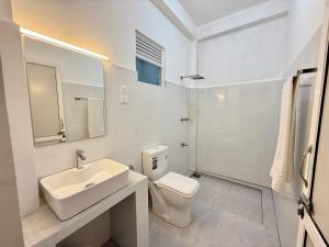 a white bathroom with a sink and a toilet at Shells Unawatuna in Unawatuna