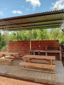two picnic tables under a pavilion with a brick wall at CABAÑAS Gaucho RIVERO in El Soberbio