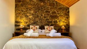 a bedroom with a bed with a stone wall at Apartamentos rurales La Pornacal I y La Pornacal II in Villar de Vildas