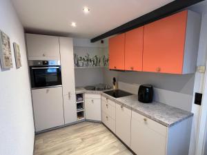 a kitchen with white and orange cabinets and a sink at Fichtelrooms in Fichtelberg