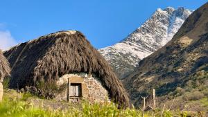 a hut with a thatched roof with a mountain in the background at Apartamentos rurales La Pornacal I y La Pornacal II in Villar de Vildas +71 photos