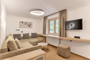 a living room with a couch and a tv at Quality Hosts Arlberg - Hotel Goldenes Kreuz B&B - Sommerkarte Premium inklusive in Sankt Anton am Arlberg