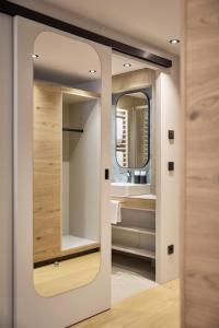 a bathroom with a mirror and a sink at Quality Hosts Arlberg - Hotel Goldenes Kreuz B&B - Sommerkarte Premium inklusive in Sankt Anton am Arlberg +62 photos