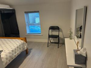 a bedroom with a bed and a chair next to a window at OMalleys Town House in Buncrana