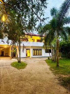 a white building with palm trees in front of it at Asiri guest house in Dickwella