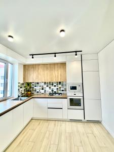 a kitchen with white cabinets and a wooden floor at Modern 3-bedroom jacuzzi apartment in Lviv +36 photos