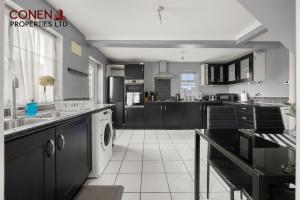 a kitchen with black cabinets and a white appliance at CONEN Morant Place in Grays Thurrock