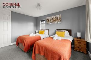 a bedroom with two beds with orange sheets at CONEN Morant Place in Grays Thurrock