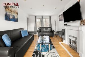 a living room with a black leather couch and a fireplace at CONEN Morant Place in Grays Thurrock