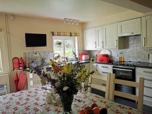 a kitchen with a table with a vase of flowers on it at The Millers Cottage in Okehampton
