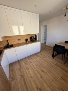 a kitchen with white cabinets and a dining table at AgA in Pobierowo +6 photos