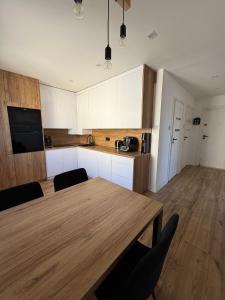 a kitchen with a wooden table and a kitchen with white cabinets at AgA in Pobierowo