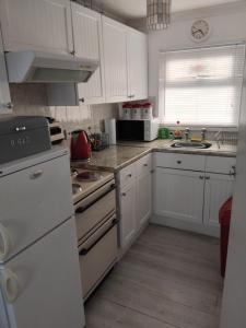 a kitchen with white cabinets and a white refrigerator at "Trinity" Chalet in Sundowner Hemsby in Hemsby