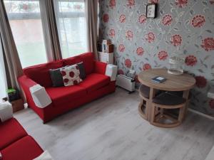 a living room with a red couch and a table at "Trinity" Chalet in Sundowner Hemsby in Hemsby